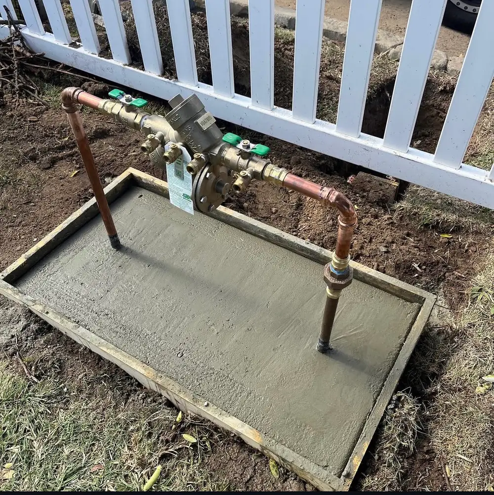 A newly installed backflow preventer on a finished concrete pad